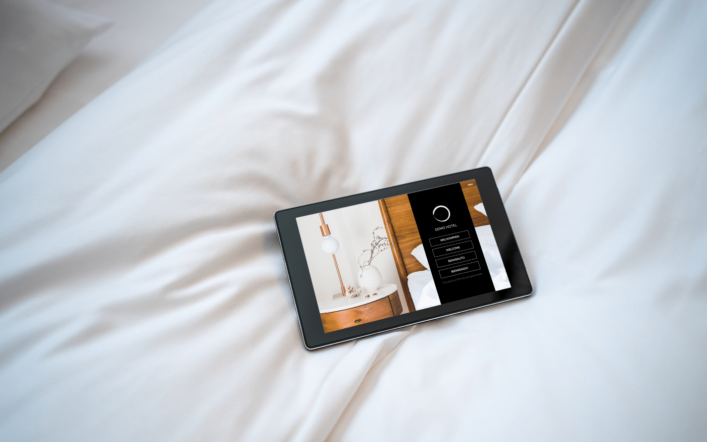 SuitePad tablet on white bed sheets